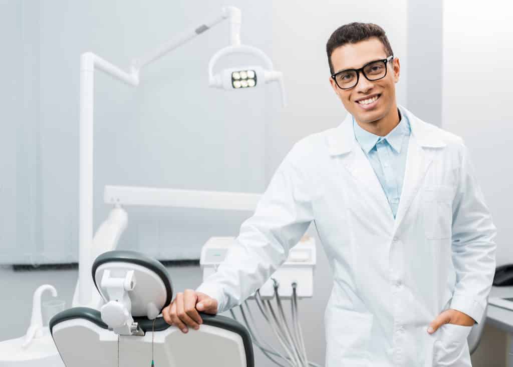dentist smiling and standing with hand in pocket